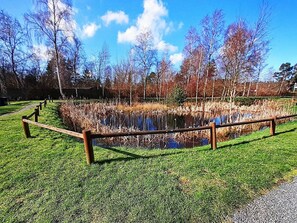 A pond with a wooden fence, surrounded by grass and trees. - Holiday Home in NykÃ¸bing Sj (Nykobing Sjaelland)