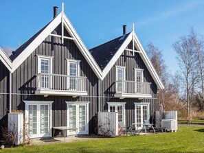 A two-story house with a balcony, a chimney, and a small outdoor seating area.