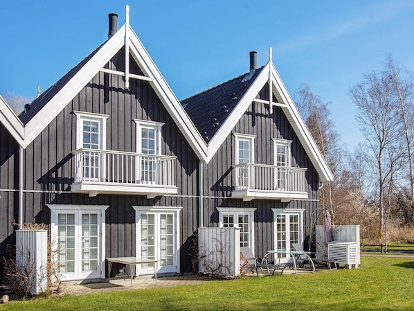 A two-story house with a balcony, a chimney, and a small outdoor seating area.