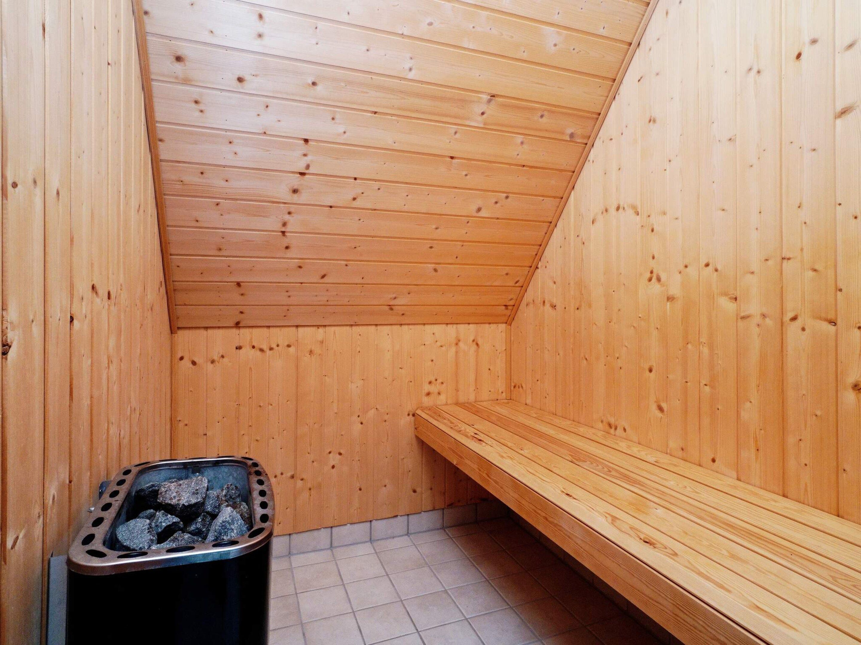 Una sala de sauna con paredes de madera y un banco.