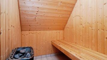 Una sala de sauna con paredes de madera y un banco.