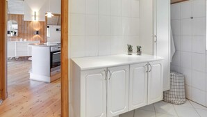 Ett modernt kök med vita skåp, en köksö i mitten och ett träpanelat tak.