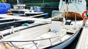 A small white boat docked at a pier with a cabin, a steering wheel, and a life ring. - 8 Person Holiday Home in Revsnes (Åfjord)