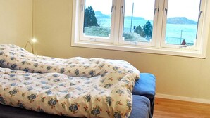 A bedroom with a bed, a window with a view of the sea, and a wooden floor. - 8 Person Holiday Home in Revsnes (Åfjord)
