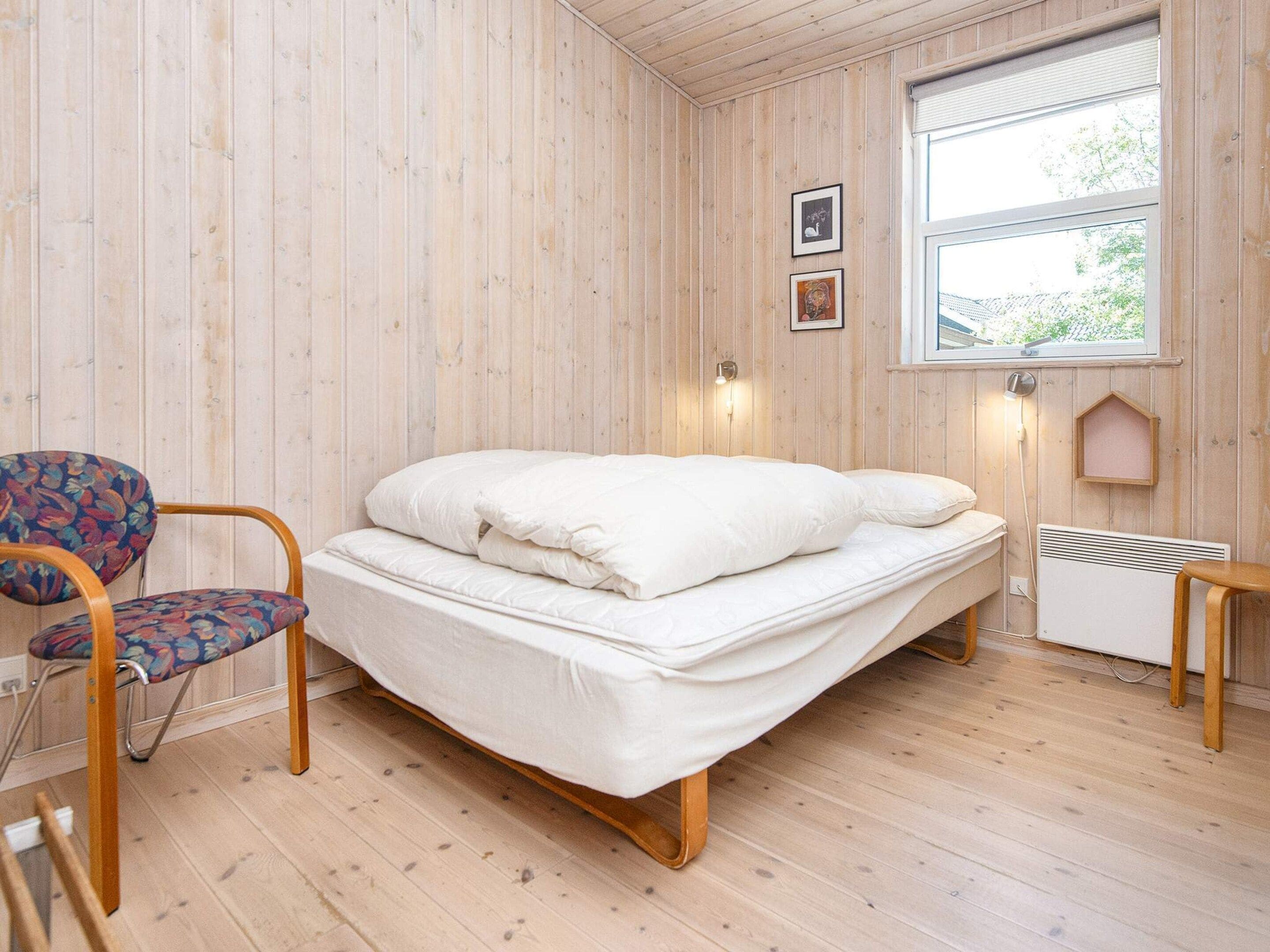 A room with a bed, a chair, a window, and a radiator.