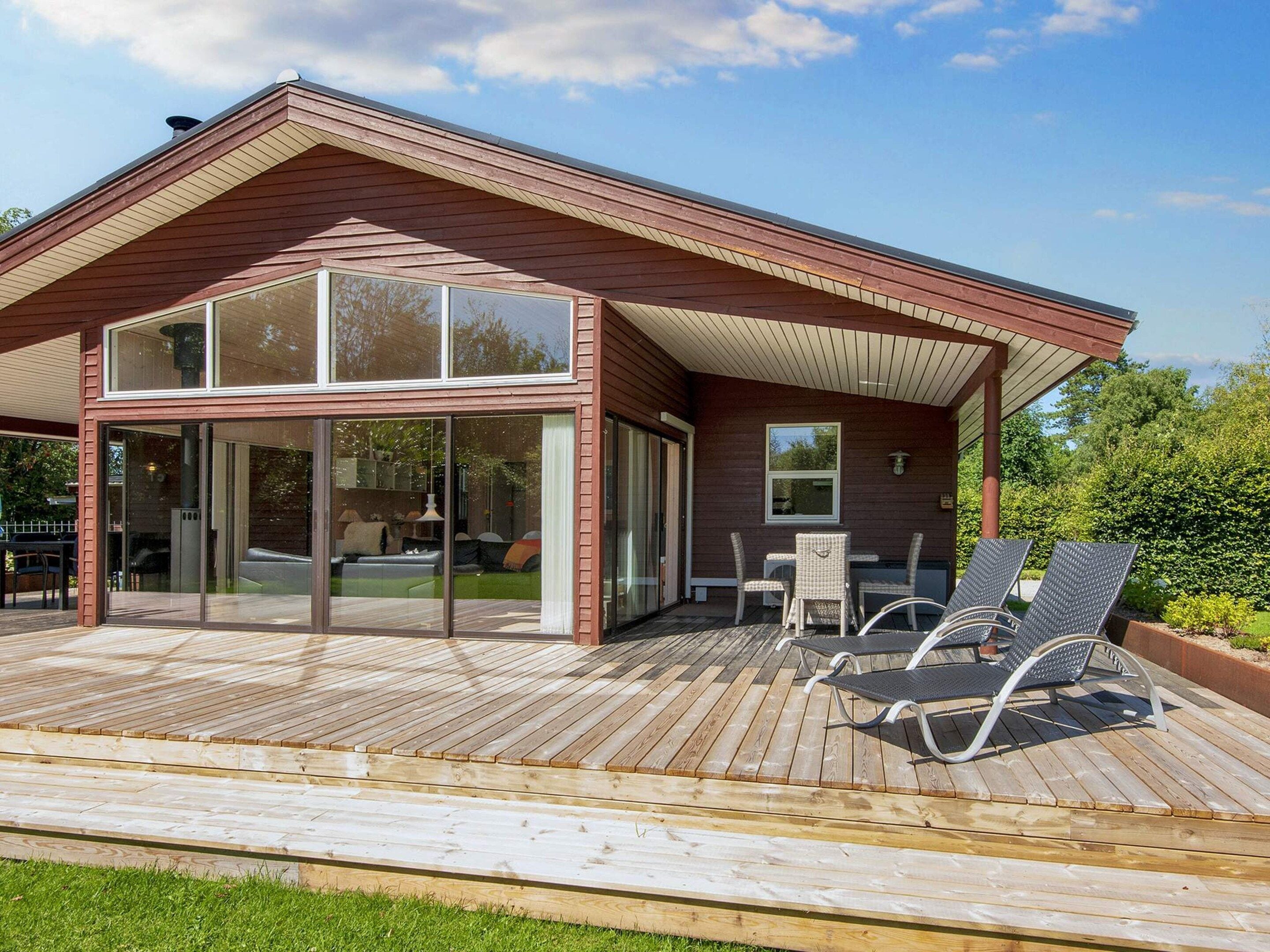 Een modern huis met een terras, grote ramen en tuinmeubilair.