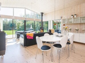 A modern interior with a fireplace, a dining area, and a view of the outdoors. - Holiday Home in Glesborg (Glesborg)
