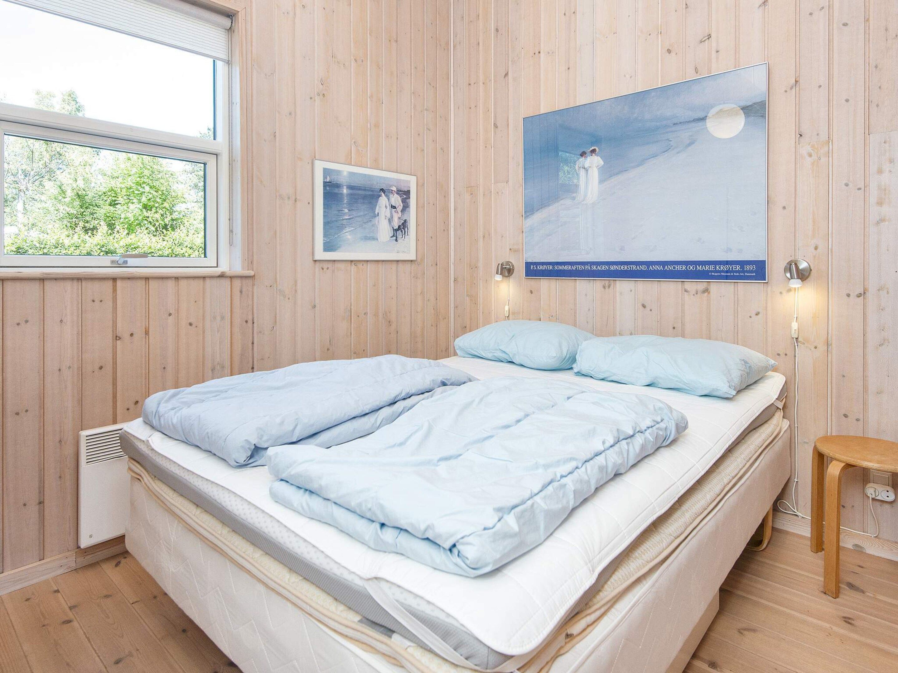 Un dormitorio con cama, mesita de noche, lámpara de pared y un cartel.