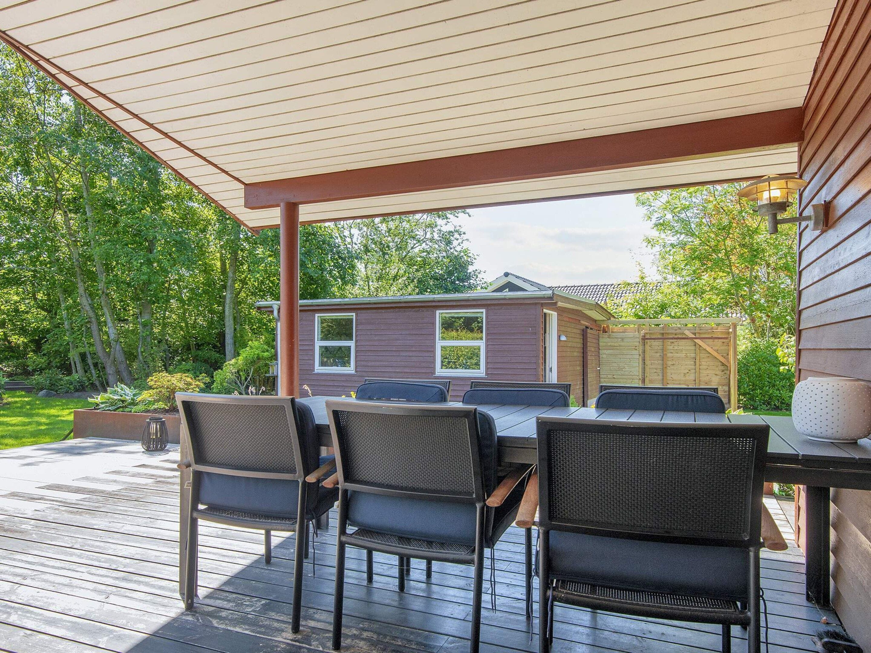 An outdoor patio with a covered seating area, a table, and chairs.