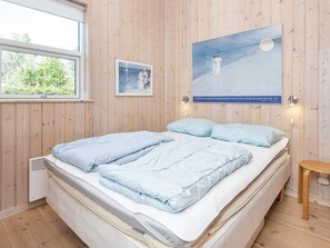 A bedroom with a bed, a small bedside table, a wall-mounted lamp, and a poster. - Holiday Home in Glesborg (Glesborg)