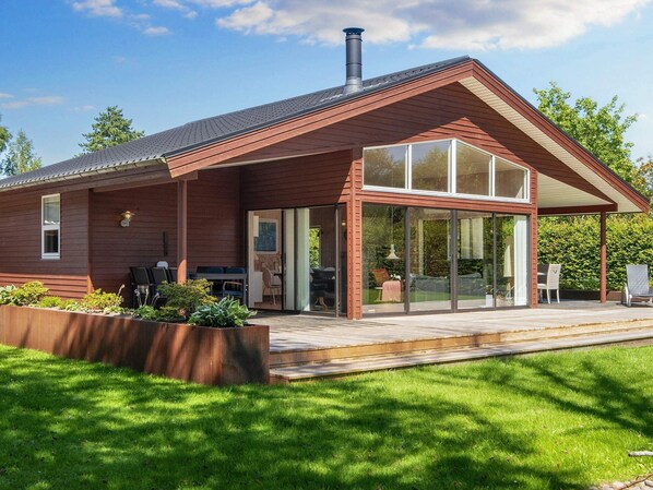 A modern house with a covered patio, large windows, and a chimney. - Holiday Home in Glesborg (Glesborg)