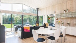 Ein modernes Wohnzimmer mit Kamin, Essbereich und großen Fenstern mit Blick ins Freie.