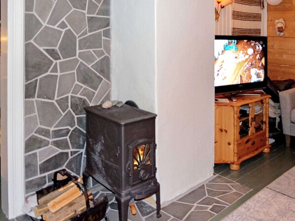 A stone wall, a wood-burning stove, and a television in a living room. - 6 Person Holiday Home in Olderdalen (Kåfjord)