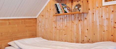 A wooden bunk bed with a shelf above containing books and a framed picture.