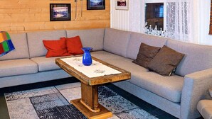 Una sala de estar con un sofá, una mesa de centro y un ventanal con cortinas.