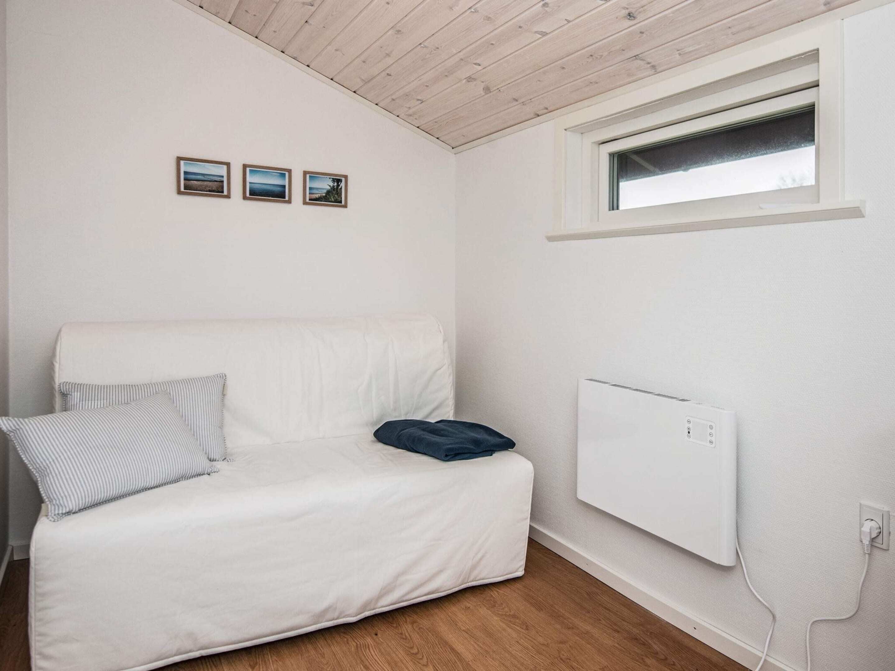 A white sofa with striped pillows, a blue pillow, and a white radiator on the wall.