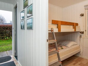 A bunk bed with a ladder, a door with a window, and a doormat.