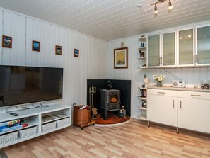 A living room with a television, a fireplace, and a kitchen area with cabinets.