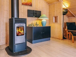 Cozy space with a wood-burning stove, modern cabinet, and wooden chair for relaxation.