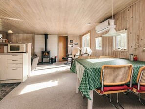 A cozy room with a wooden interior, a dining table with chairs, a fireplace, and a kitchenette. - 5 Person Holiday Home in Hurup Thy (Hurup Thy)