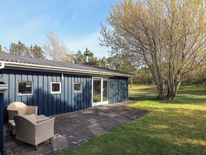 A blue building with a patio, a chair, and a tree. - 5 Person Holiday Home in Hurup Thy (Hurup Thy)