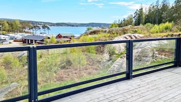 A wooden deck with a metal railing overlooking a lakeside area with RVs and buildings.