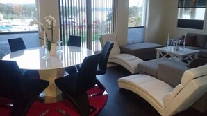A modern living room with a round table, sofas, and a large window with a view of a body of water. - 4 Star Holiday Home in Stromstad (Stromstad)