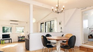 A modern kitchen with white cabinetry, a wooden dining table with black chairs, and a chandelier. - 6 Person Holiday Home in Follenslev (Follenslev)