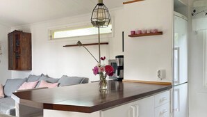 Una cocina moderna con encimera de madera, armarios blancos, una cafetera y un jarrón con flores.