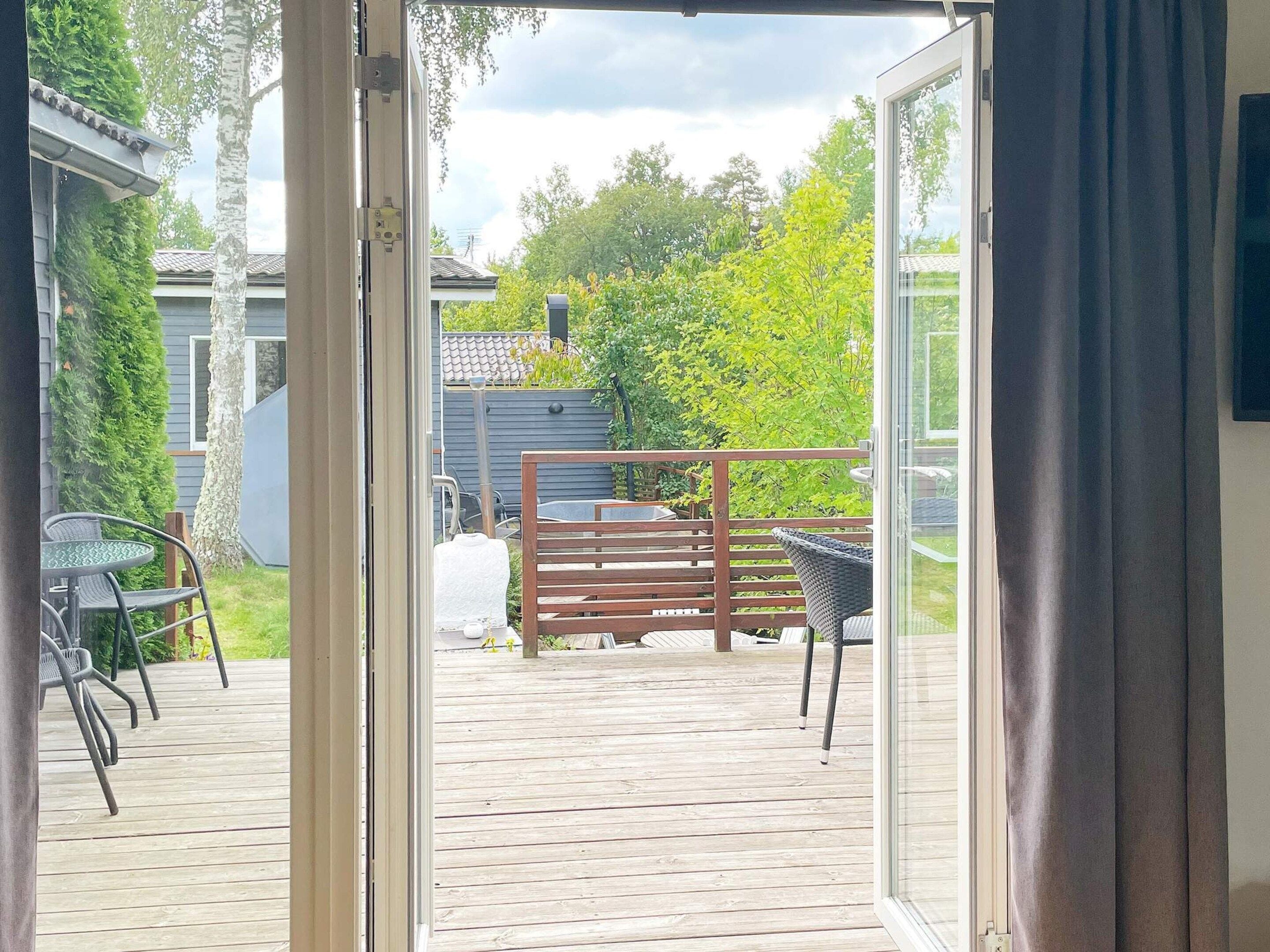 An open door leading to a wooden deck with outdoor furniture.