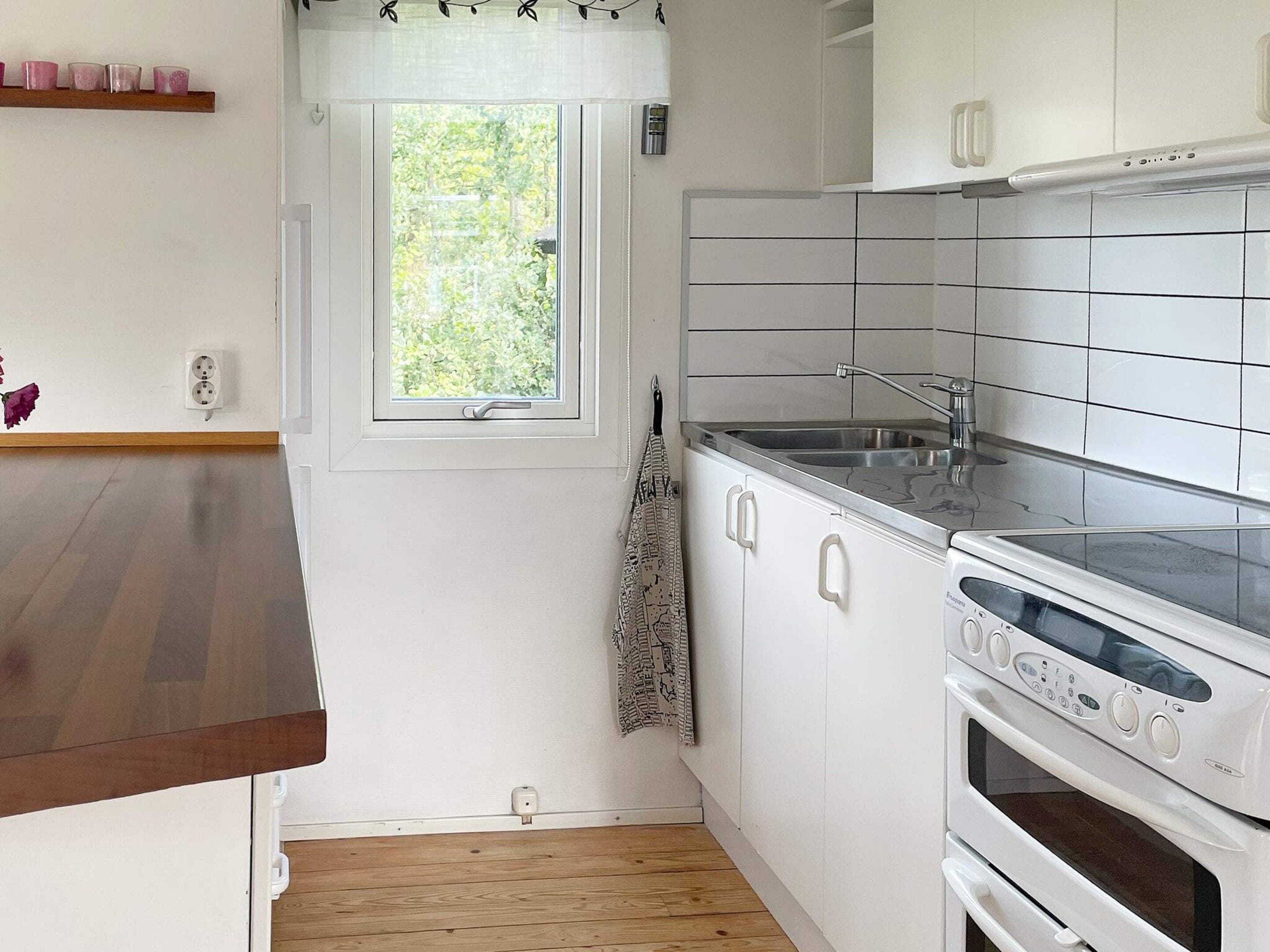 Een keuken met witte kastjes, een roestvrijstalen spoelbak en een inbouwoven.
