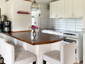 A modern kitchen with a wooden island, white cabinets, a stainless steel range, and a coffee maker. - 6 Person Holiday Home in Granna (Gränna)