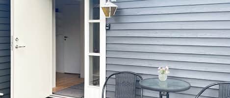 An open door leading to a room with a window, a small table with chairs, and a decorative vase.