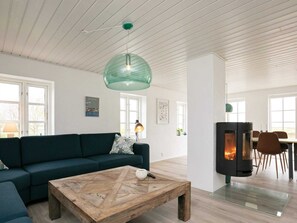 A modern living room with a sofa, coffee table, and a wood-burning stove. - Holiday Home in NykÃ¸bing M (Nykobing Mors)