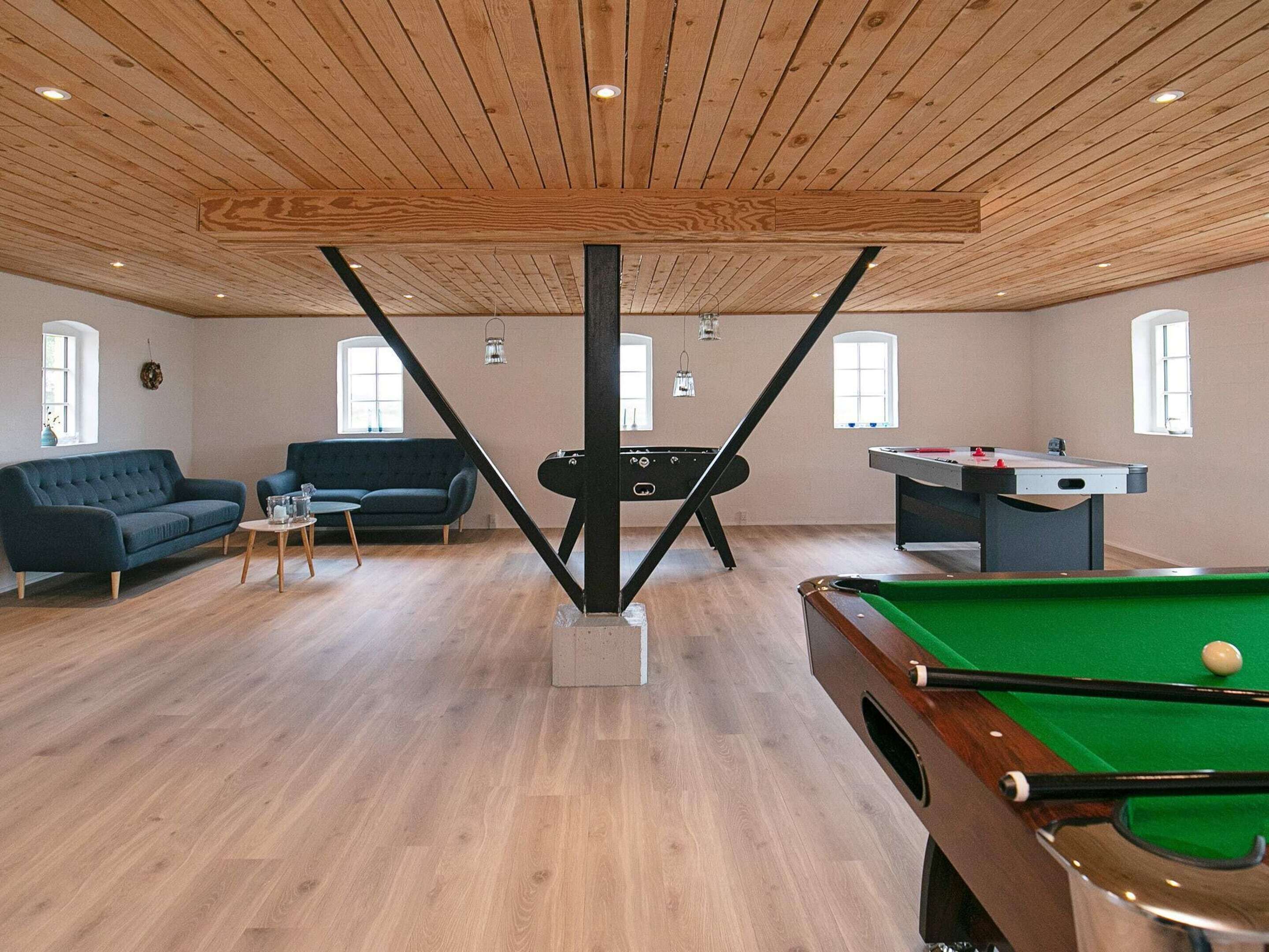 A room with a pool table, a sofa, and a billiards table.