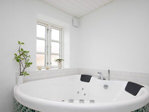 A modern bathroom with a freestanding bathtub, a window with white frames, and a potted plant on the windowsill. - Holiday Home in NykÃ¸bing M (Nykobing Mors)