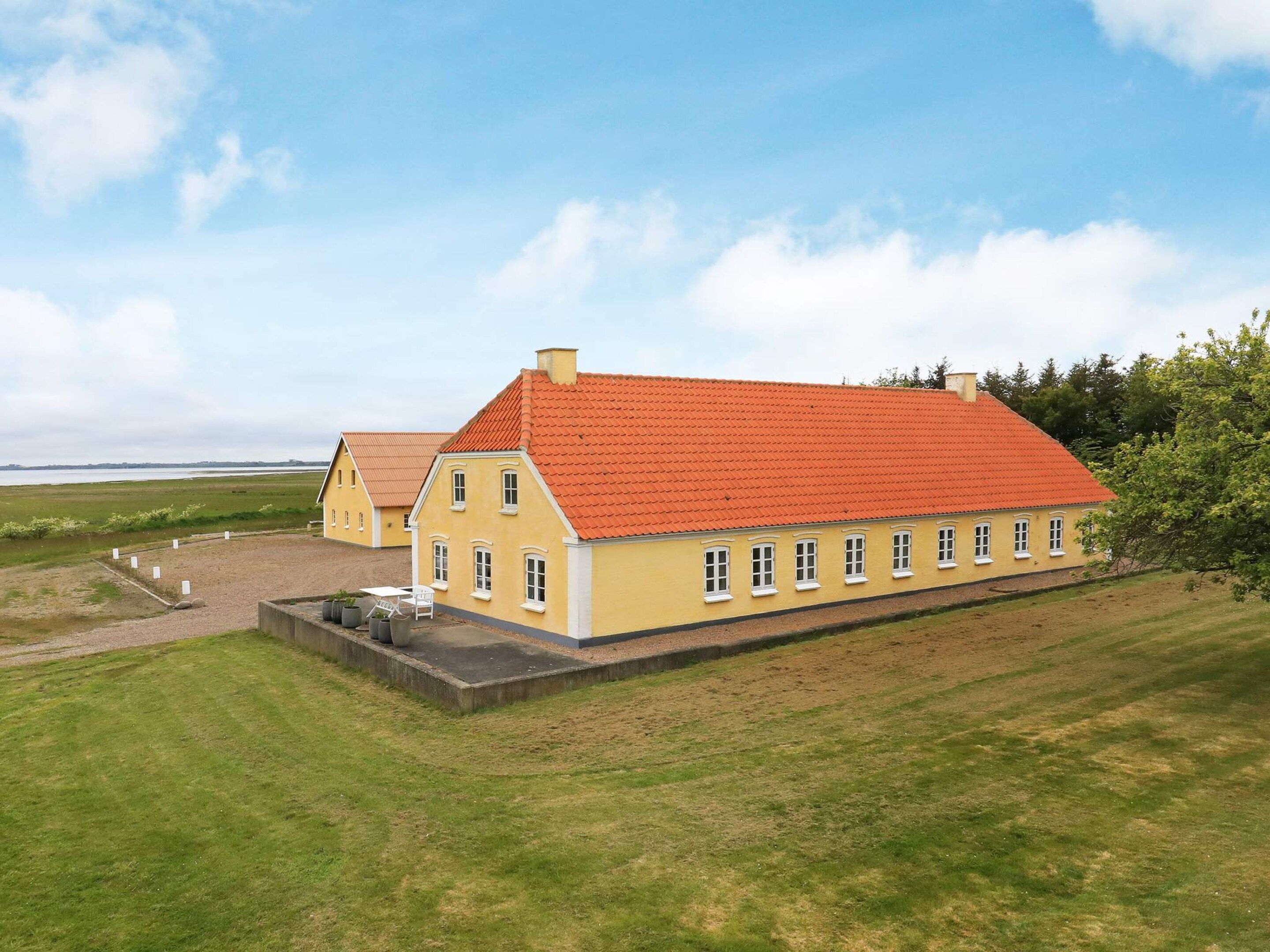 Een geel gebouw met een rood dak, omgeven door groen gras en bomen.
