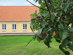 A building with a yellow facade and a red-tiled roof, surrounded by a grassy area. - Holiday Home in NykÃ¸bing M (Nykobing Mors)