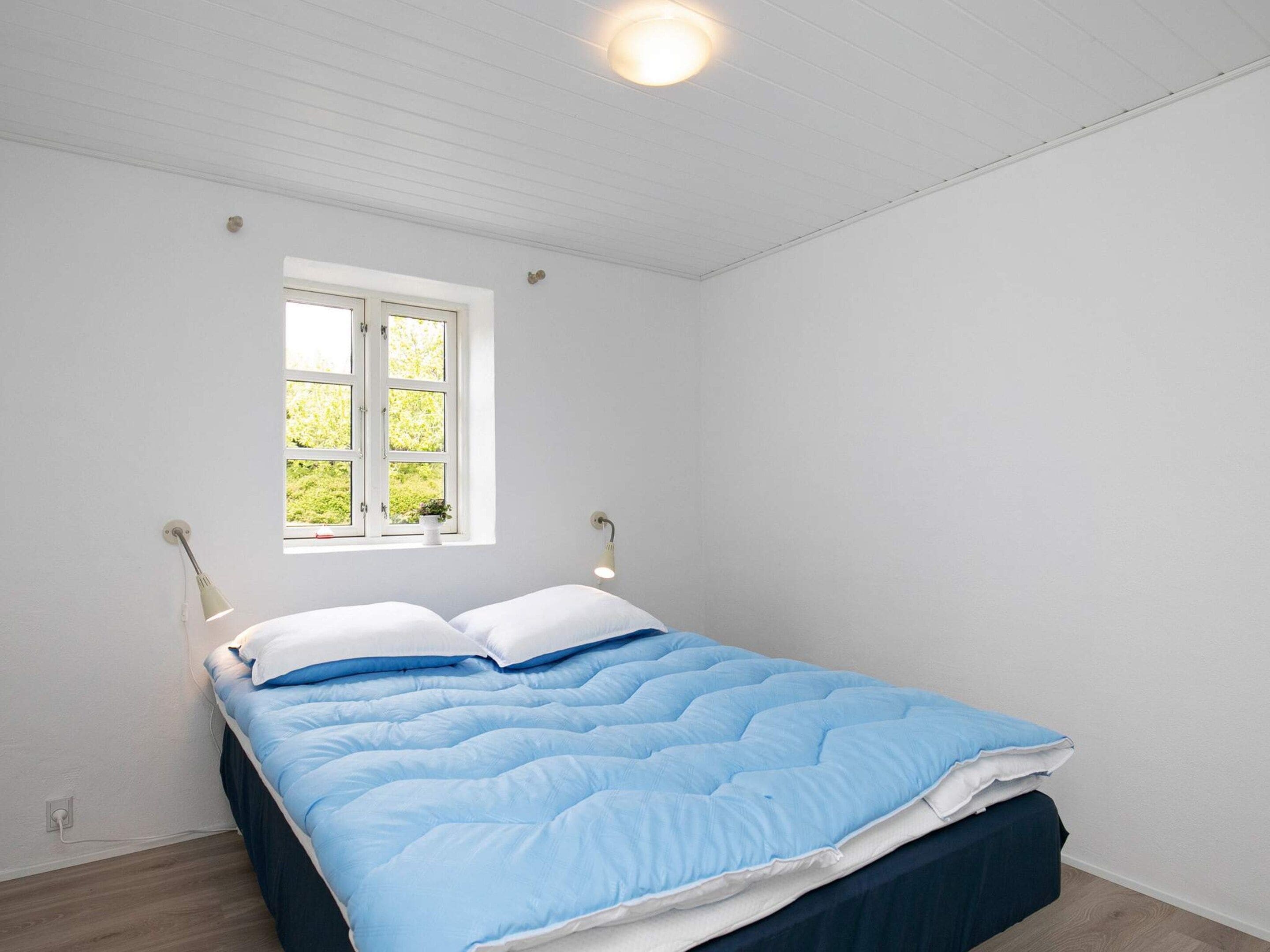 A bedroom with a bed, a window, and a ceiling light.