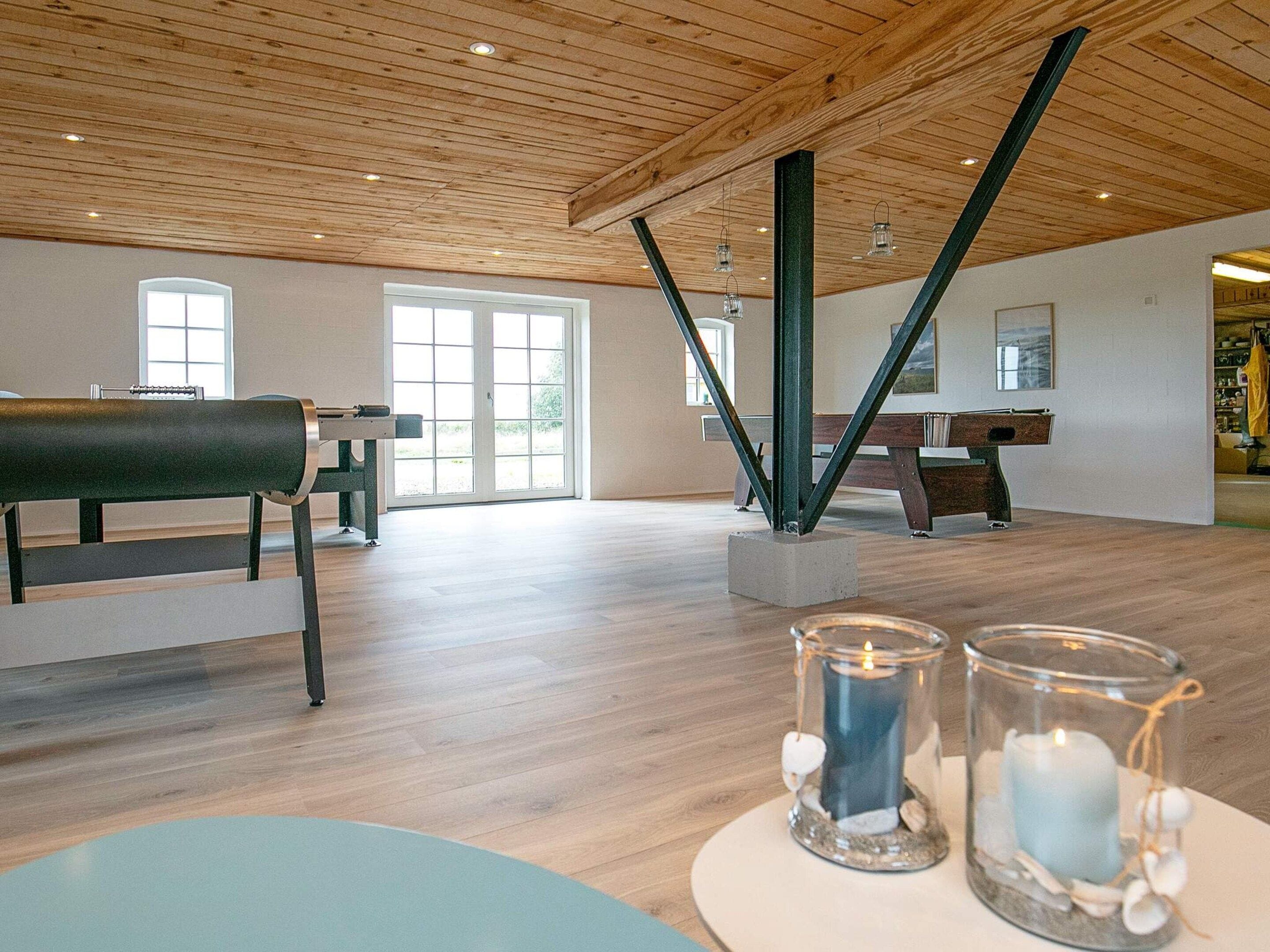 A spacious room with a wooden ceiling, a piano, and a glass table with candles.