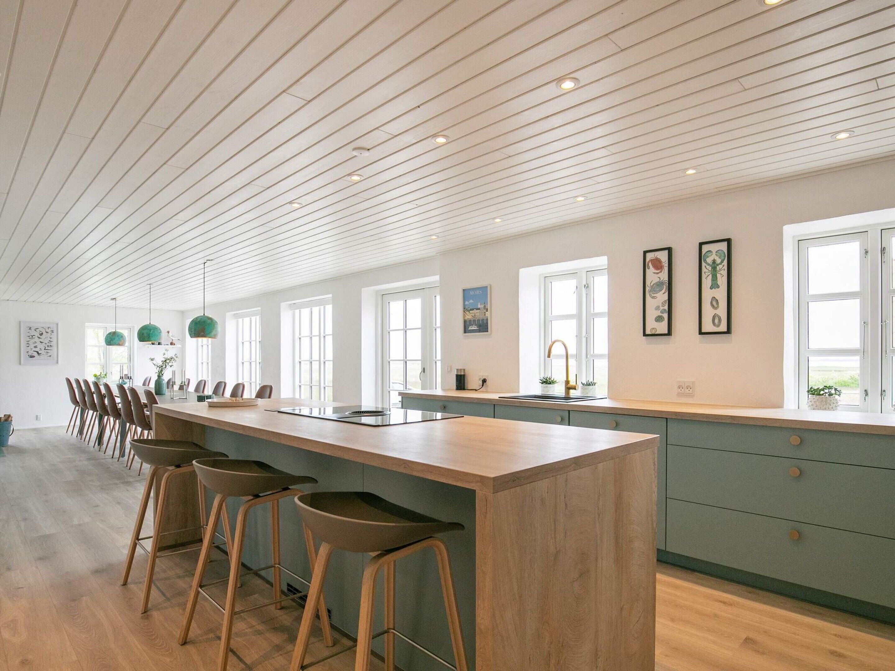 Cozinha espaçosa com uma ilha grande, banquetas de bar e vista para o exterior.