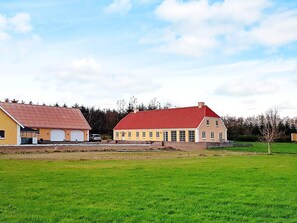 A two-story building with a red roof and yellow walls, adjacent to a green field. - Holiday Home in NykÃ¸bing M (Nykobing Mors)