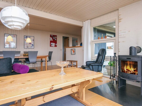 Una sala de estar acogedora con una mesa de madera, sillas, una chimenea y un comedor con mesa y sillas.