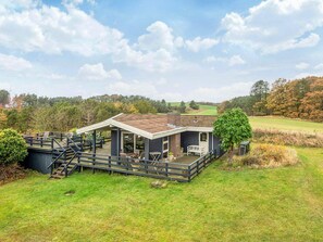 A house with a deck, a covered patio, and a view of a golf course. - 6 Person Holiday Home in Knebel (Knebel)
