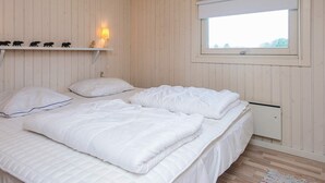 A bedroom with a bed, a window, a shelf with figurines, and a lamp. - 6 Person Holiday Home in Knebel (Knebel)