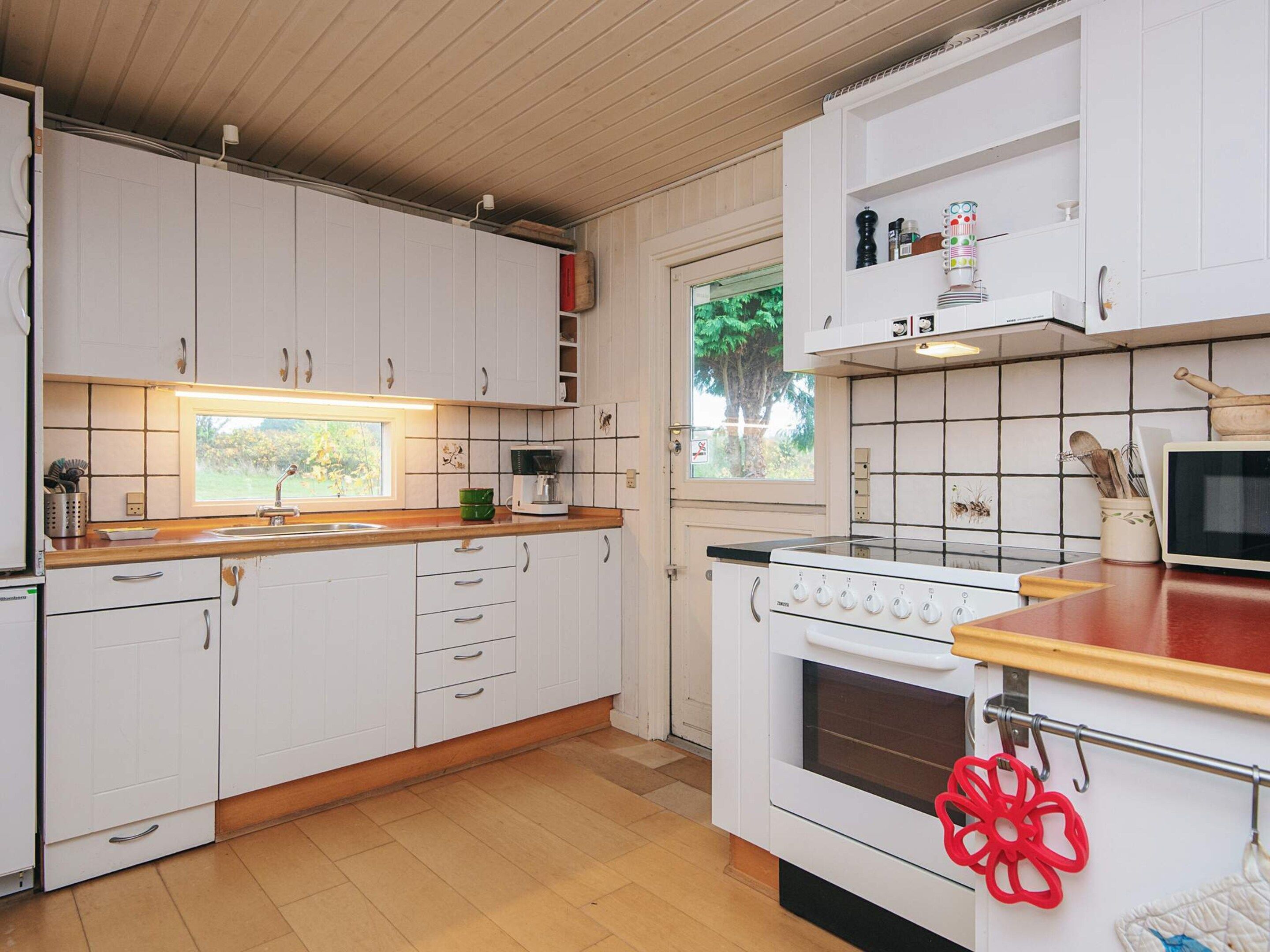 A kitchen with white cabinets, a wooden countertop, a stove, and a microwave.