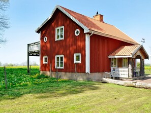A red wooden house with a balcony, a porch, and a field in the background. - 8 Person Holiday Home in Granna (Gränna)
