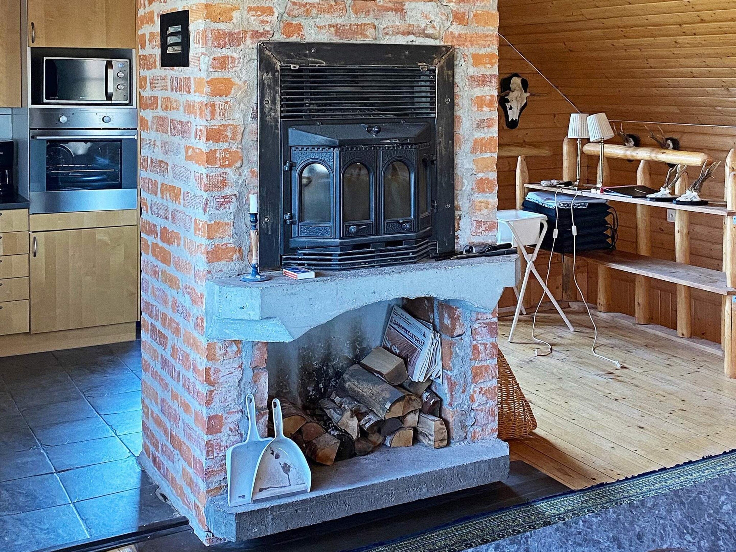 A kitchen with a brick fireplace, a microwave, and a stove.