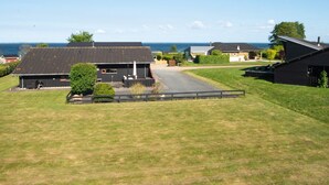 A rural property with multiple buildings, a grassy area, and a view of the sea.