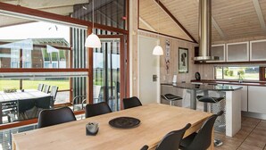 A modern kitchen with a large island, wooden flooring, and a dining area with a table and chairs.